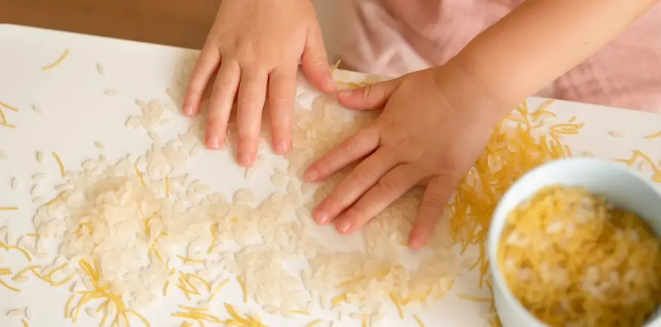 Dziecko bawiące się ziarenkami ryżu w żłobku