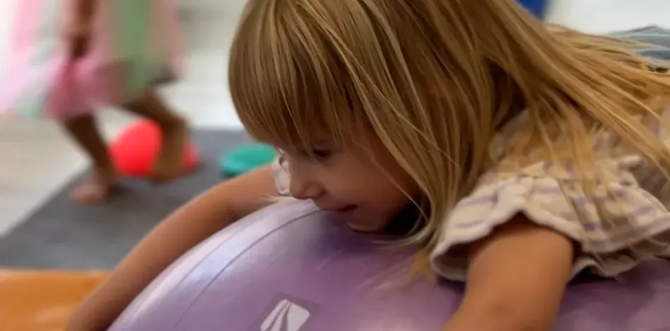 Dziewczynka bawiąca się na pompowanej piłce w przedszkolu